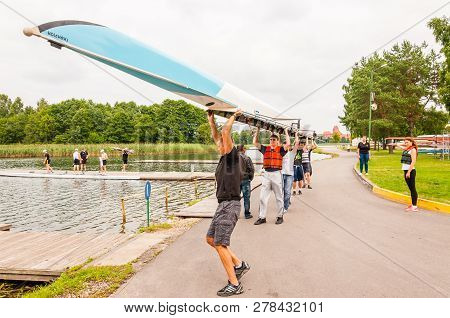 Trakai, Lithuania - July 26, 2013: Eight People Carrying An Eight That Is A Rowing Boat Used In The 