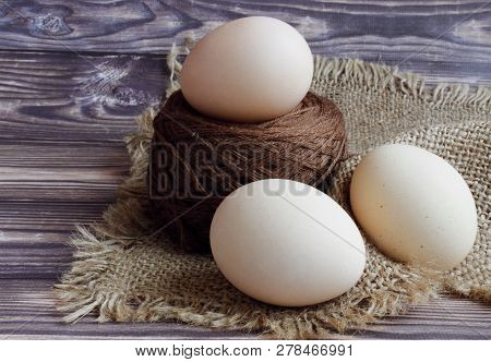 One Easter Egg Lies On Top Of The Yarn, Next To Two More. Below Them Is A Beautiful Beige Napkin