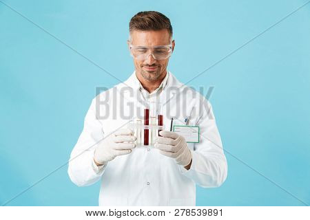 Photo of a handsome mature man doctor posing isolated over blue wall background holding test tubes with blood.