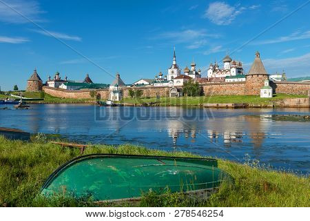 Old Fishing Boats On The Shore Against The Background Of The Transfiguration Of The Solovetsky Monas