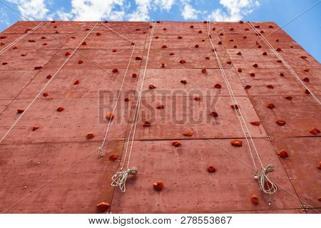 Artificial rock climbing wall with grips for hands and feet in outdoor adventure park used to practise lead climbing or bouldering
