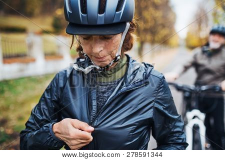 Active Senior Couple With Electrobikes Standing Outdoors On A Road In Park.