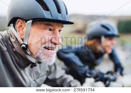 Active Senior Couple With Electrobikes Cycling Outdoors On A Road In Nature.