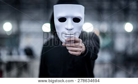 Mystery Hoodie Man With Black Mask Holding White Mask In His Hand. Anonymous Social Masking Or Bipol