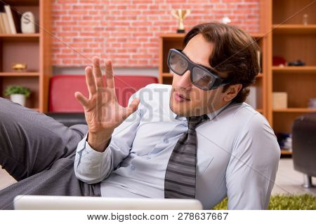 Young employee with virtual glasses during break in the office 