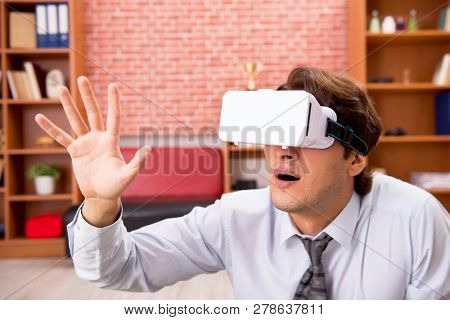 Young employee with virtual glasses during break in the office 