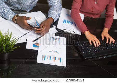 Hands Of Black People Holding Mobile Phone On Background Of Financial Documents In Business Space Cl