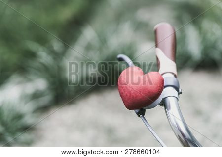A Little Red Heart Pillow On The Bicycle Handlebar.