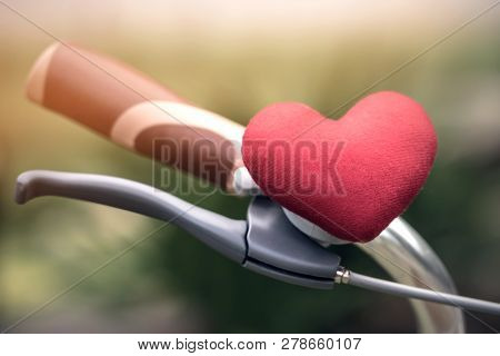 A Little Red Heart Pillow On The Bicycle Handlebar.