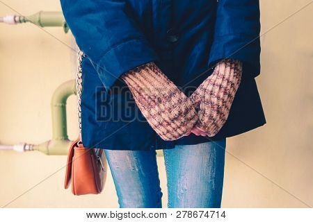 Girl In Jeans And Knitted Gloves Standing In Front Of Green Wall With Leaser Bag On Shoulder