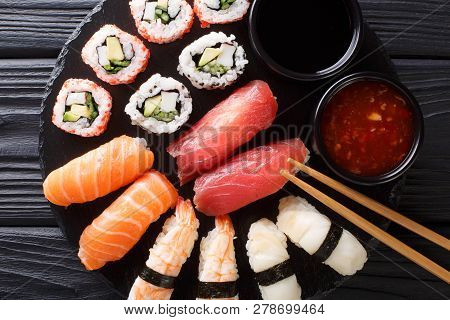 Set Of Japanese Rolls Of Uramak And Nigiri Served With Two Sauces Close-up On A Slate. Horizontal To