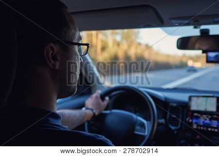 Man Driving A Car And Using Navigator In His Cellphone. Insight View. He Use Glasses.