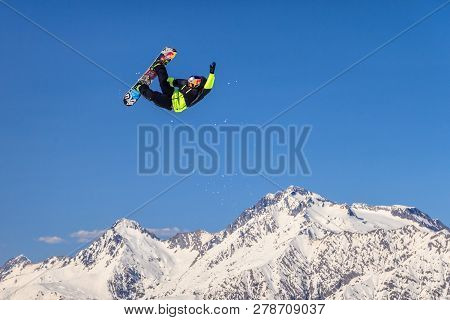 Sochi, Russia - March 25, 2014: Man Snowboarder Flies Freestyle From Big Air Jump Making Trick On Ch