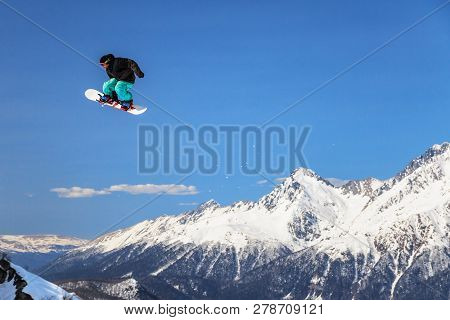 Sochi, Russia - March 25, 2014: Man Snowboarder Flies Freestyle From Big Air Jump Making Trick On Ch