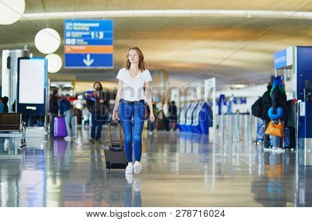 Young Woman In International Airport Walking With Luggage, Ready For Her Flight