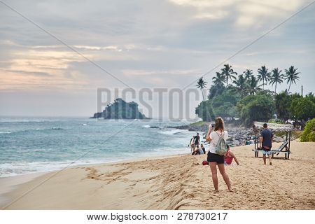 Girl Taking Pictures Of The Sunset. Midigama Beach. Sunset In The Indian Ocean. Midigama, Sri Lanka.