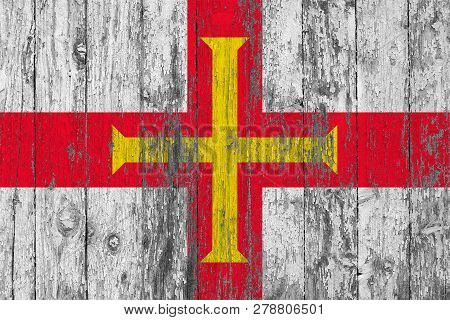 Flag Of Guernsey Painted On Worn Out Wooden Texture Background.