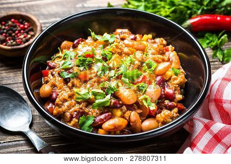 Chili Con Carne From Meat, Beans And Vegetables On Dark Wooden Table. Traditional Mexican Food.