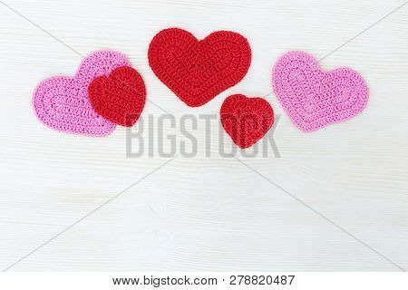 Valentine ’s Day Background Concept. Knitted Hearts On White Wooden Background With Copy Space.