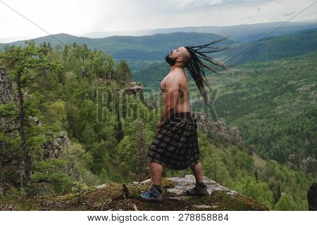 Celt On The Edge Of A Cliff In The Woods Waving His Head With Dreadlocks
