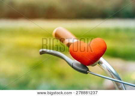 A Little Red Heart Pillow On The Bicycle Handlebar.
