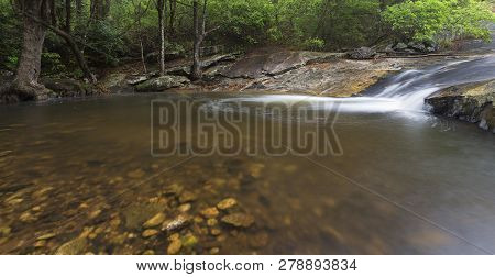 River Flowing Over Wet Rocks And The Debengeni Waterfall