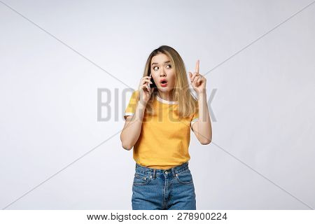 Portrait Of A Pensive Young Asian Woman Holding Mobile Phone And Looking Away Thinking Isolated Over