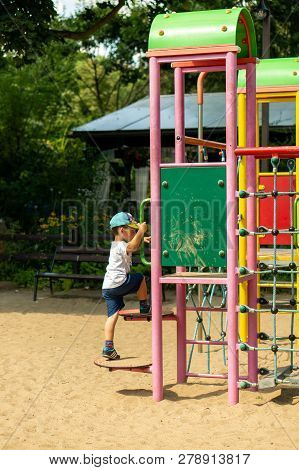 Poznan, Poland - July 29, 2018: Young Boy Climbing Some Steps Of A Equipment On A Sunny Summer Day. 