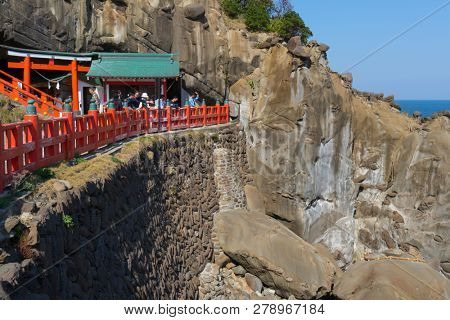 Miyazaki, Japan - November 6, 2018: People try to throw small ceramic undama, or lucky balls in a target marked by a rope at Udo Shrine  to earn good luck