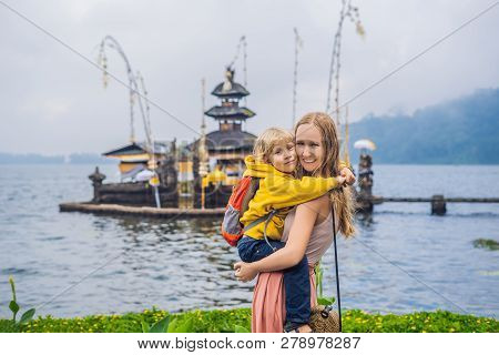 Mom And Son In The Background Of Pura Ulun Danu Bratan, Bali. Hindu Temple Surrounded By Flowers On 