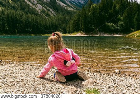Tragoess, Styria, Austria - 12.07.2020 Child Sitting At Shore Of Beautiful Lake Called Green Lake, G