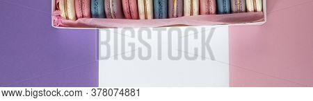Multicolored Macarons In A White Box On A White, Pink, Violet Background