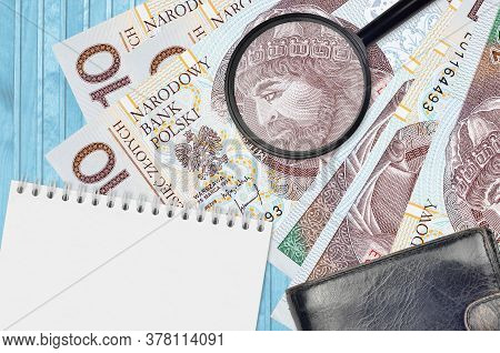 10 Polish Zloty Bills And Magnifying Glass With Black Purse And Notepad. Concept Of Counterfeit Mone
