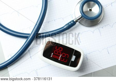 Modern Fingertip Pulse Oximeter, Stethoscope And Cardiogram On Grey Table, Flat Lay