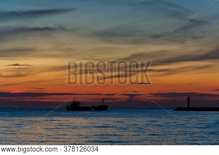 Sunset By The Sea - An Evening Landscape By The Sea Coast And A Ship Going From The Port