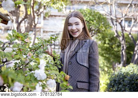 Young Long Hair Woman Model Of Clothes In The Garden In Spring Posing