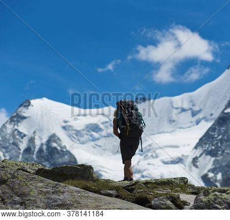 Zinal, Switzerland - July 19, 2019: Back View Of Traveler With Backpack Hiking Alone In Mountainous 