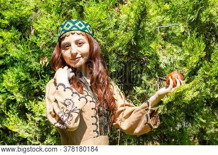Armenian Young Woman In Traditional Clothes In The Forest With Pomegranate