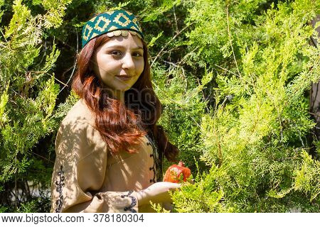Armenian Young Woman In Traditional Clothes In The Forest With Pomegranate