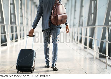 Unrecognizable Business Man Making Trip For Work Walking With Luggage Back To Camera In Airport Indo