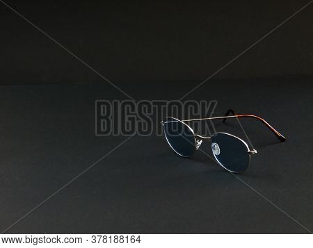 Glasses In Gray Frames With Blue Lenses On A Black Background