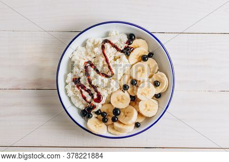 Organic Cottage Cheese With Date Syrup And Banana For Healthy Breakfast. White Wooden Table. Top Vie