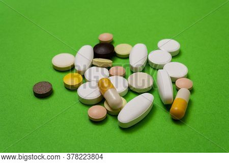 Many Colorful Round Pills And Capsules On A Green Background Close Up, Macroshot Tablets, Isolated. 