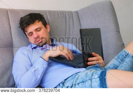 Tired Man Sleeping After Working On Laptop Sitting On Couch At Home With Computer In Hands, Freelanc