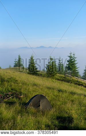Vertical Shot Of Tourist Tent Laid Out On A Green Hill In The Summer Mountains In Sunny Morning Faci