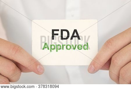 Hand Holding A Paper Fda Approved On Green Background
