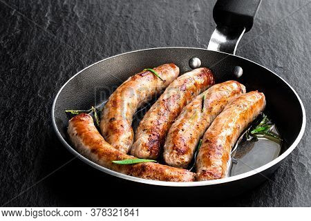 Delicious  Pork Chipolatas Sausages In A Frying Pan On Black Stone Background