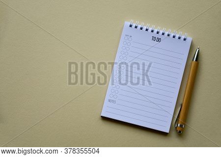 Notepad With Wooden Pen On A Beige Paper Background. Top View. Close-up. Flat Lay.