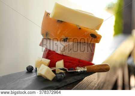 Different Types Of Delicious Cheeses And Fork On Wooden Railing Outdoors, Closeup