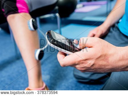Physical Therapist Install Electrostimulator On The Muscles Of The Legs.